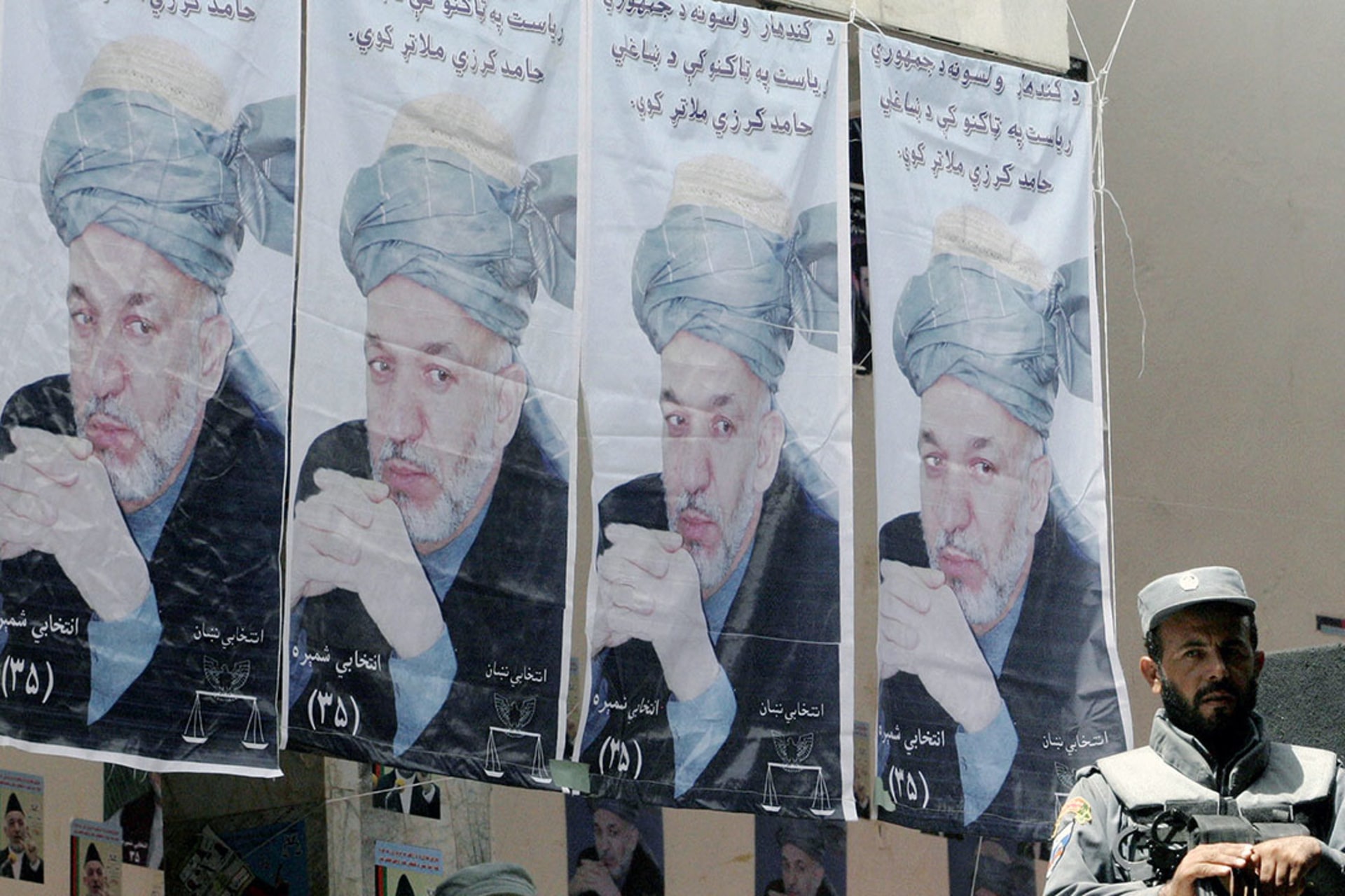 An Afghan policeman with campaign photos of Hamid Karzai. 
