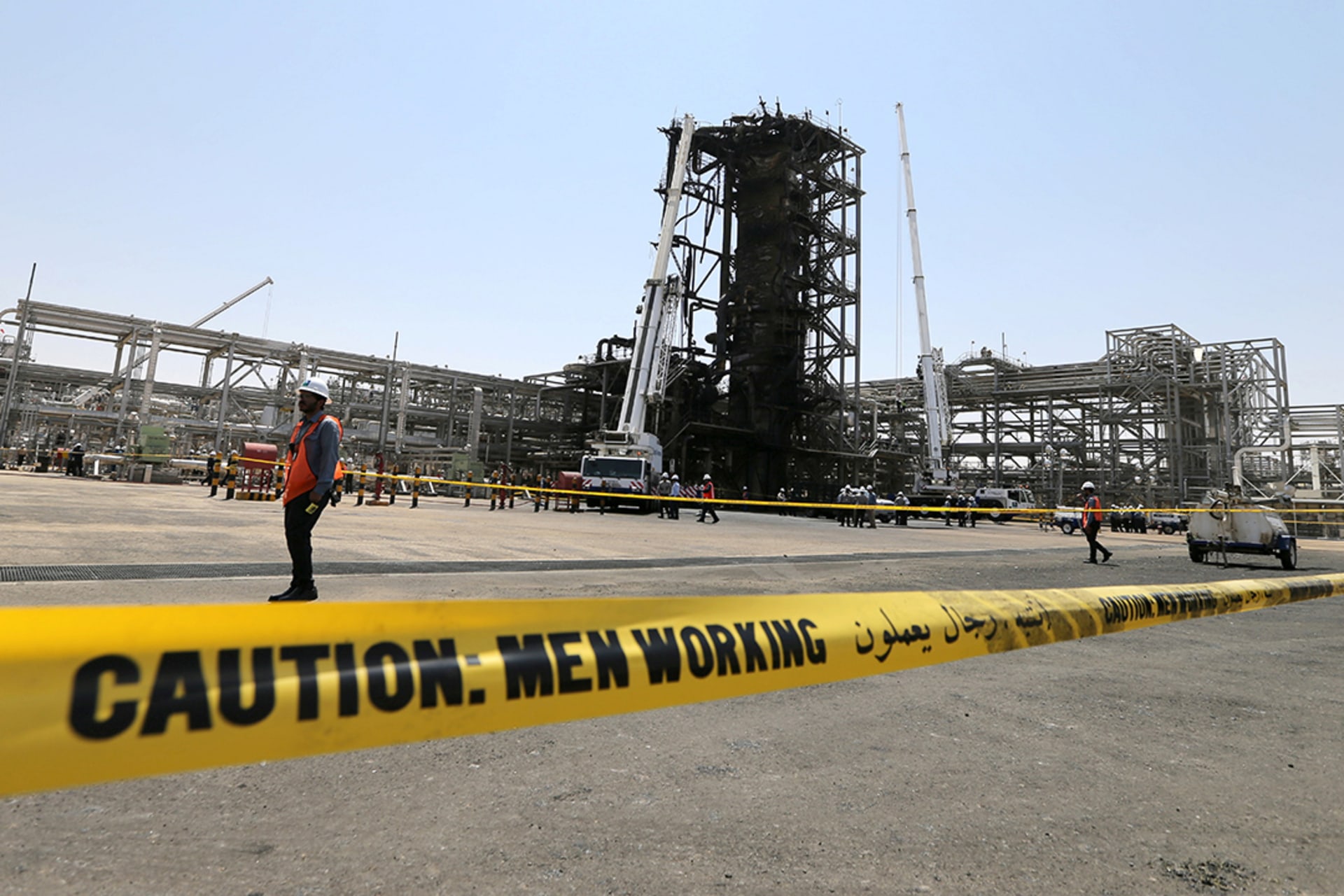 Workers examine a damaged Saudi Aramco oil facility in Khurais, Saudi Arabia. 