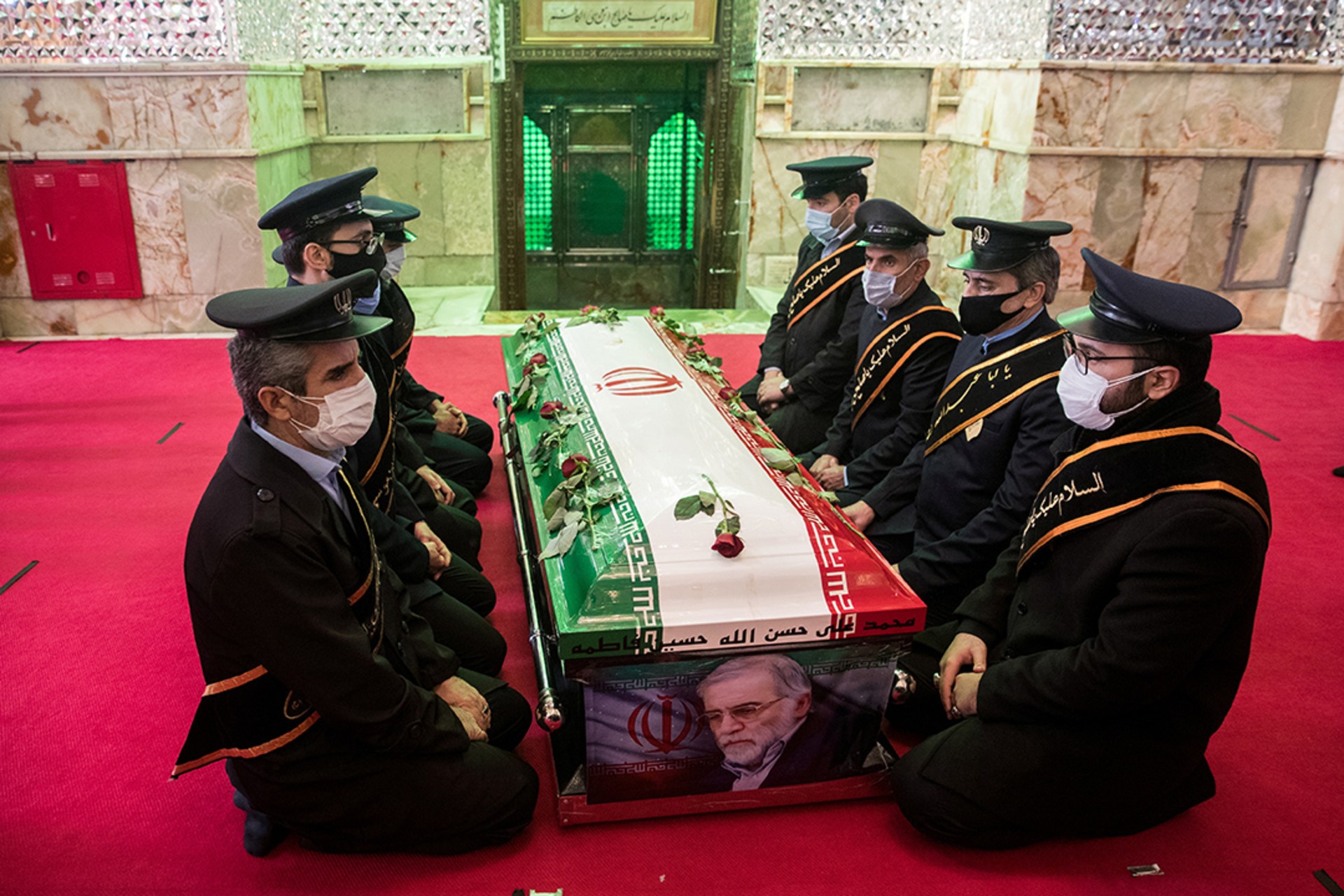 Mourners sit next to the coffin of Iranian nuclear scientist Mohsen Fakhrizadeh during the burial ceremony in Tehran, Iran.