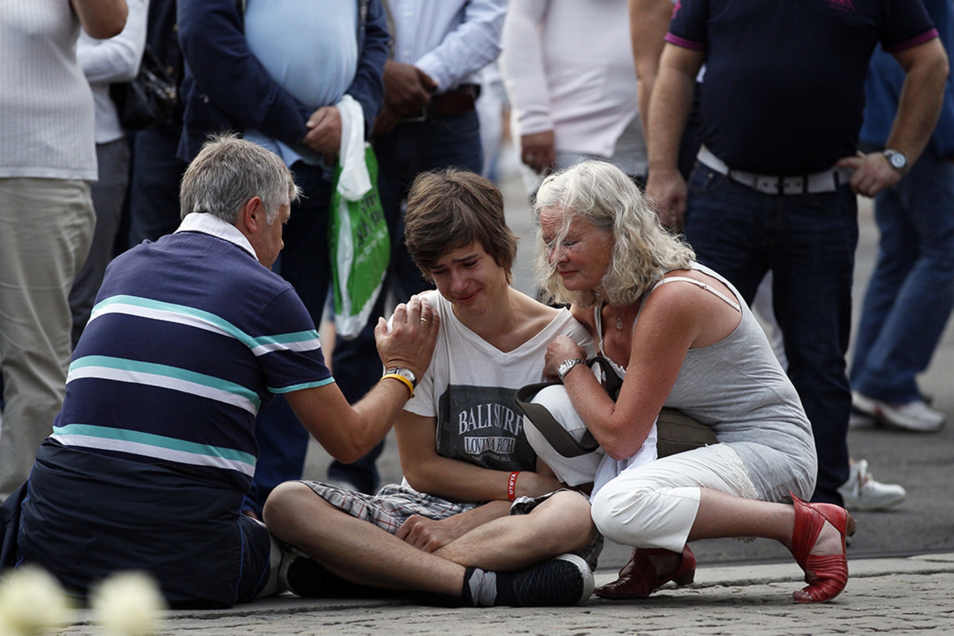A young man is comforted as he mourns the deaths of those killed by Anders Breivik in a mass shooting and bombing in Norway.