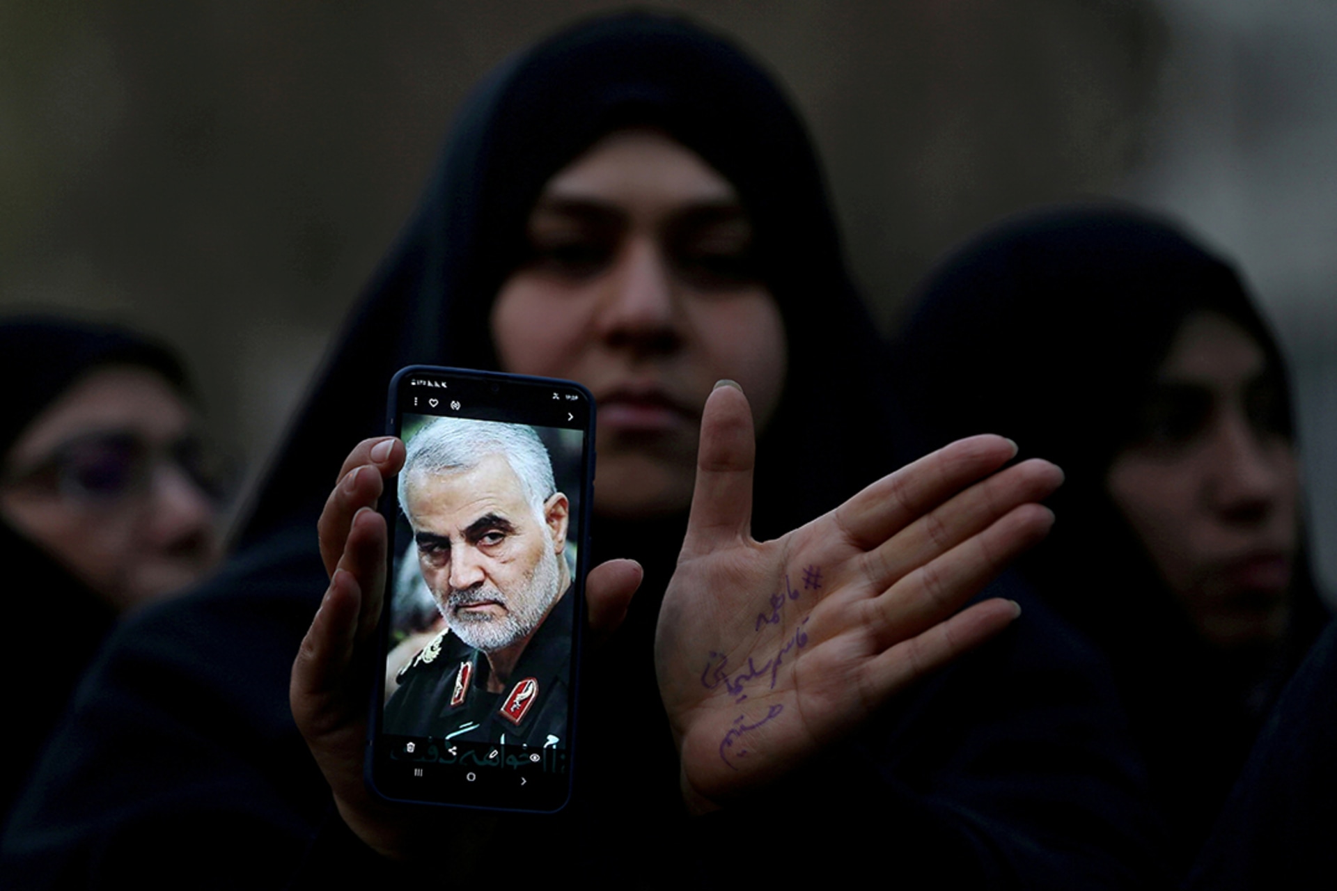 An Iranian woman shows a photo of Iranian Commander Qasem Soleimani during a protest against his killing. Nazanin Tabatabaee/WANA/Reuters