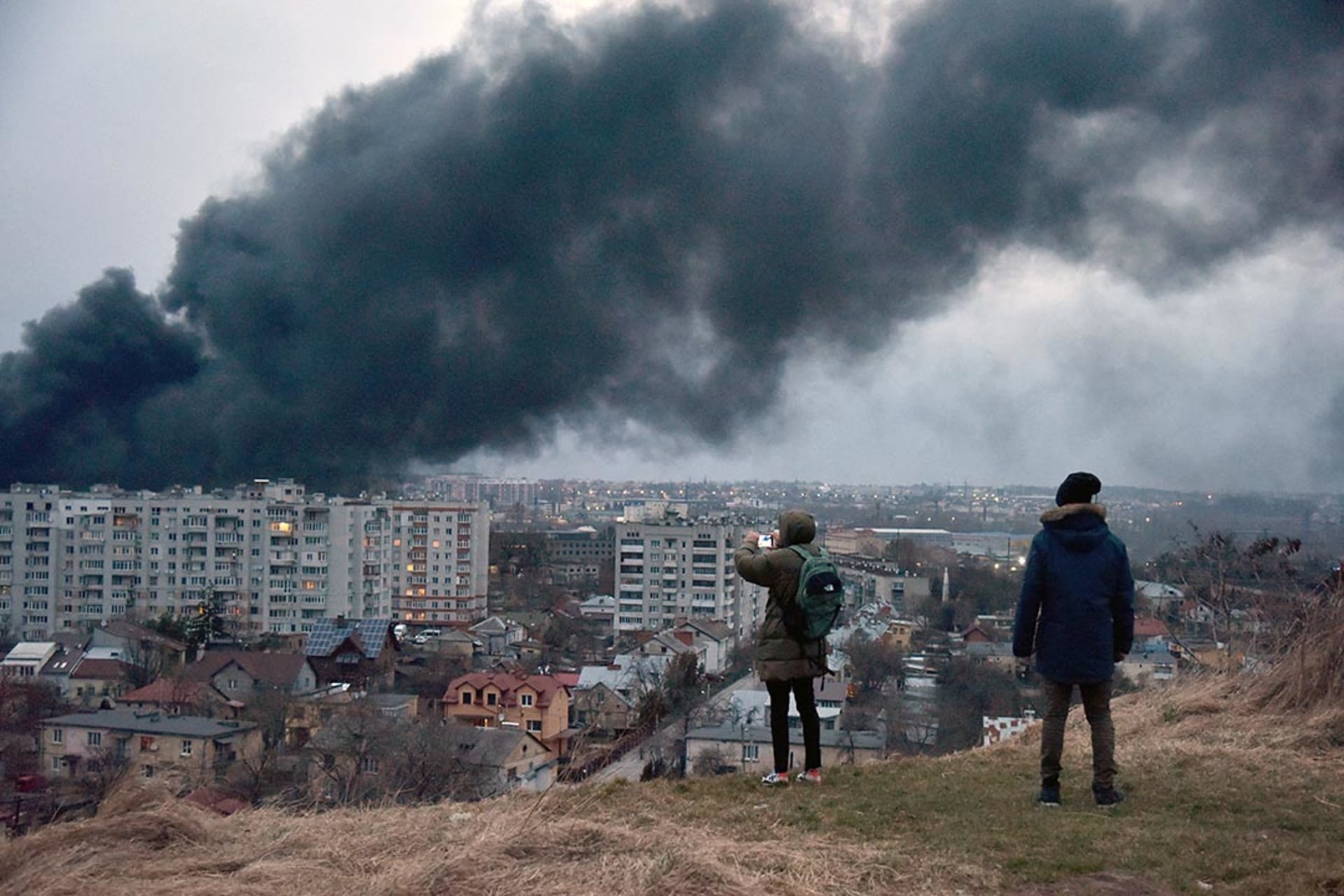People watch as smoke rises after a Russian airstrike hits Lviv, Ukraine, on March 26, 2022. 

