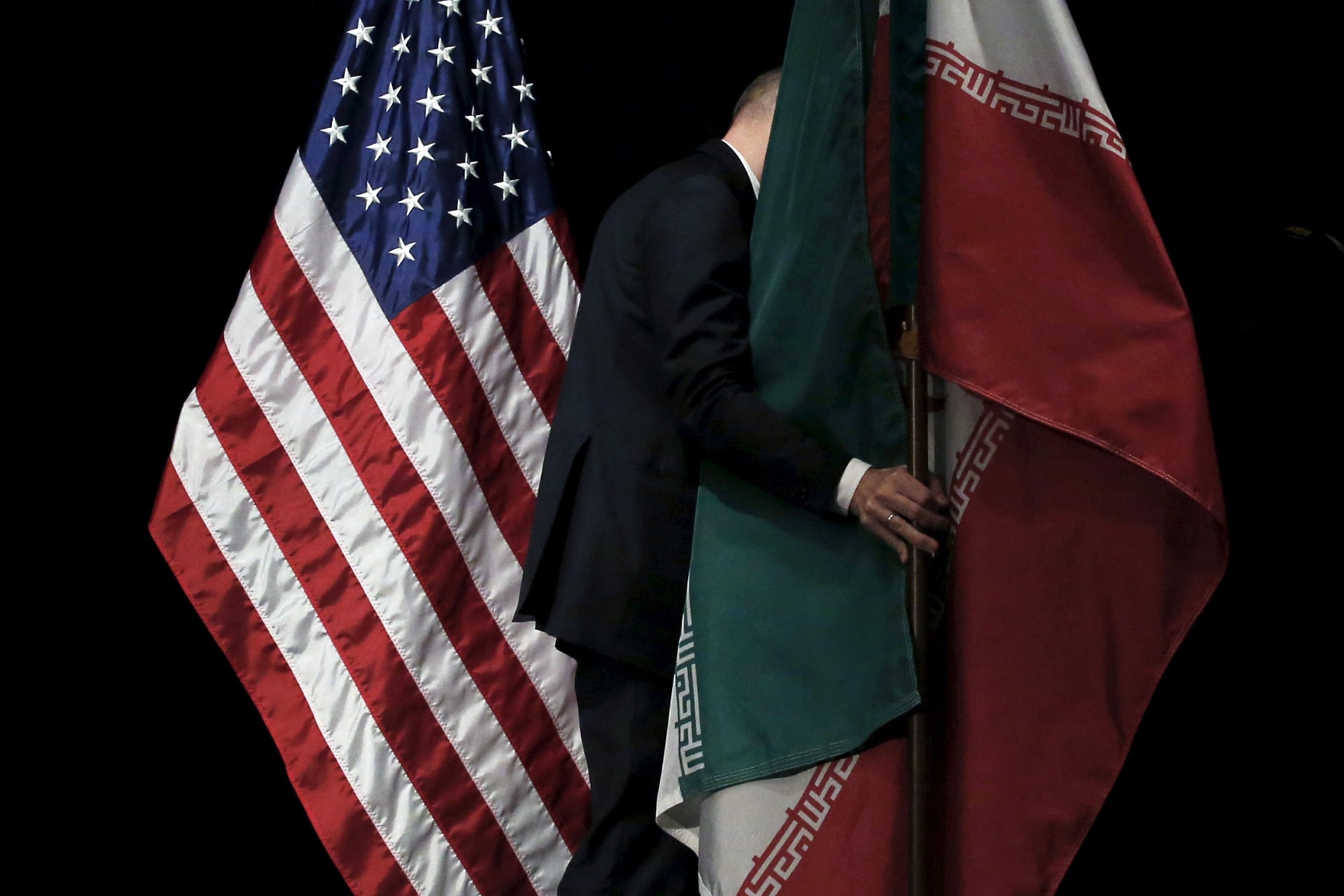 A staff removes the Iranian flag from the stage after a group picture with foreign ministers and representatives during the Iran nuclear talks at the Vienna International Center in Vienna