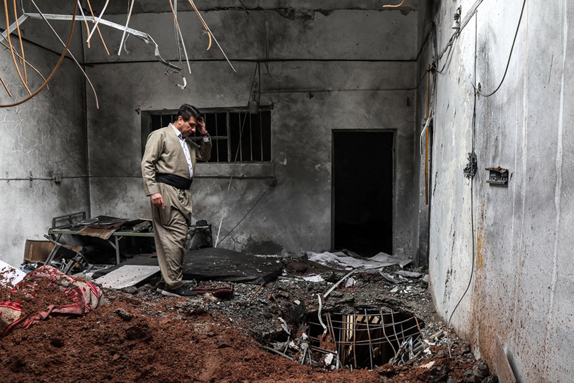 A member of the Kurdistan Democratic Party of Iran (KDPI) inspects damage at the party headquarters following an Iranian cross-border attack. 