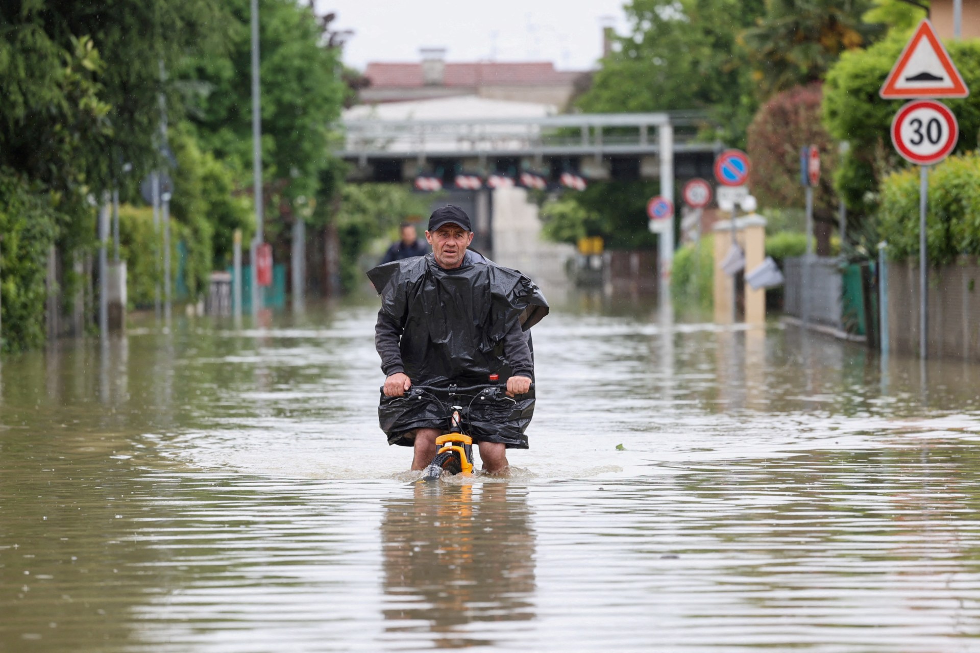 <p>A man rides on a bicycle through floodwaters after heavy rains hit Italy’s Emilia Romagna region, May 19, 2023.</p>
