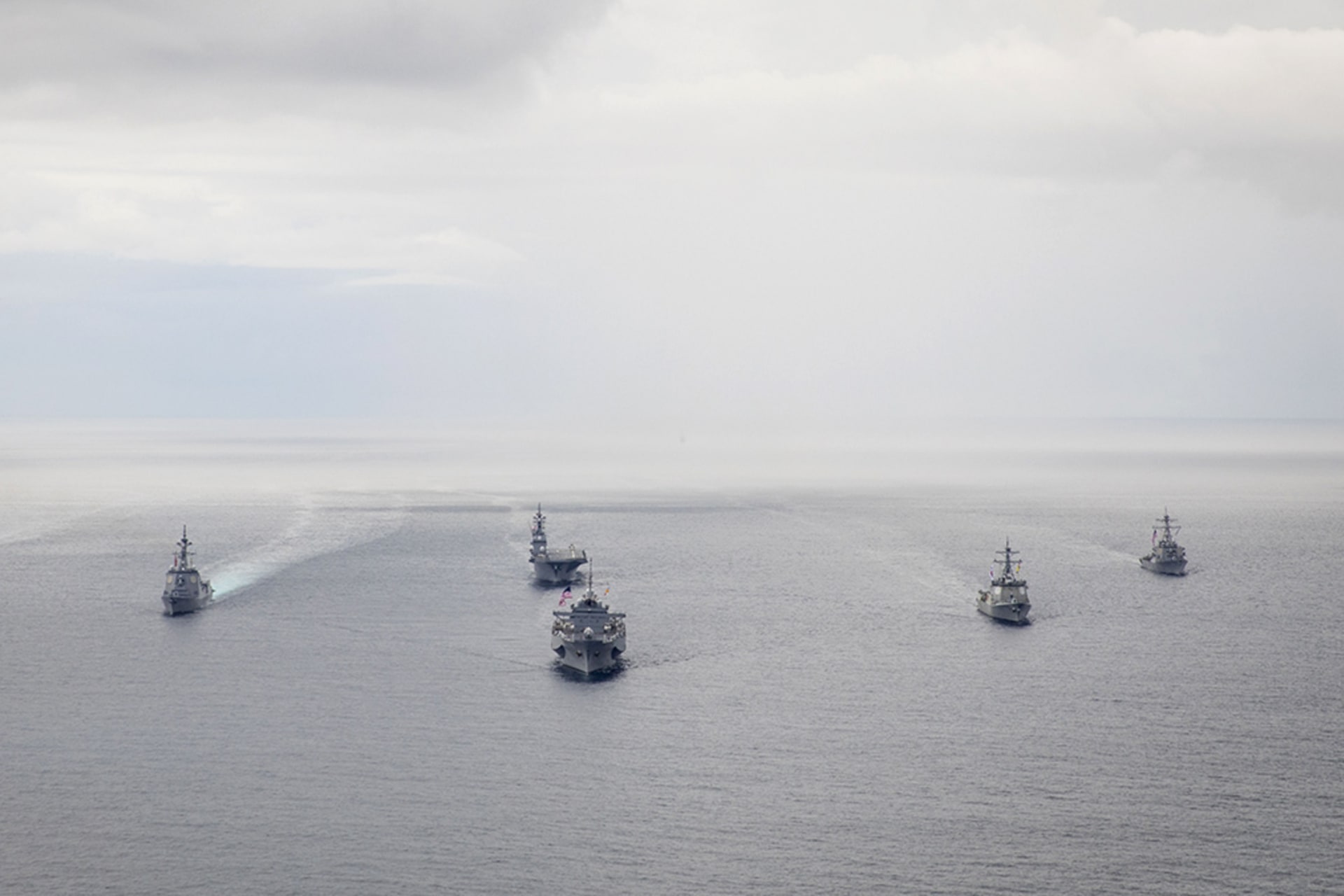 Several U.S. naval vessels cruising on open water.