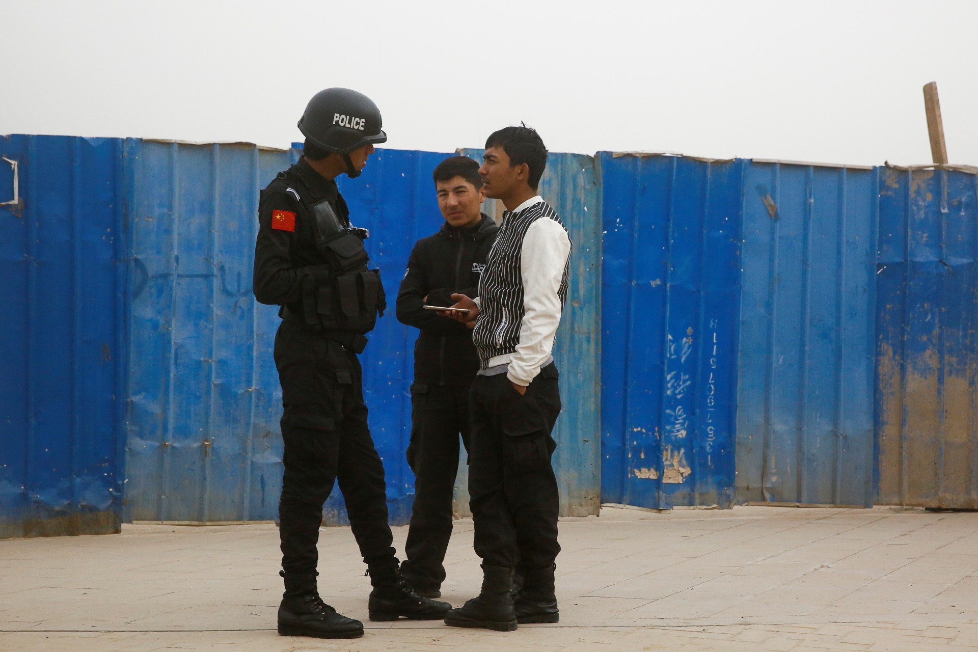 <p>A police officer talks to men in a street in Kashgar, Xinjiang Uighur Autonomous Region, China, March 24, 2017. </p>
