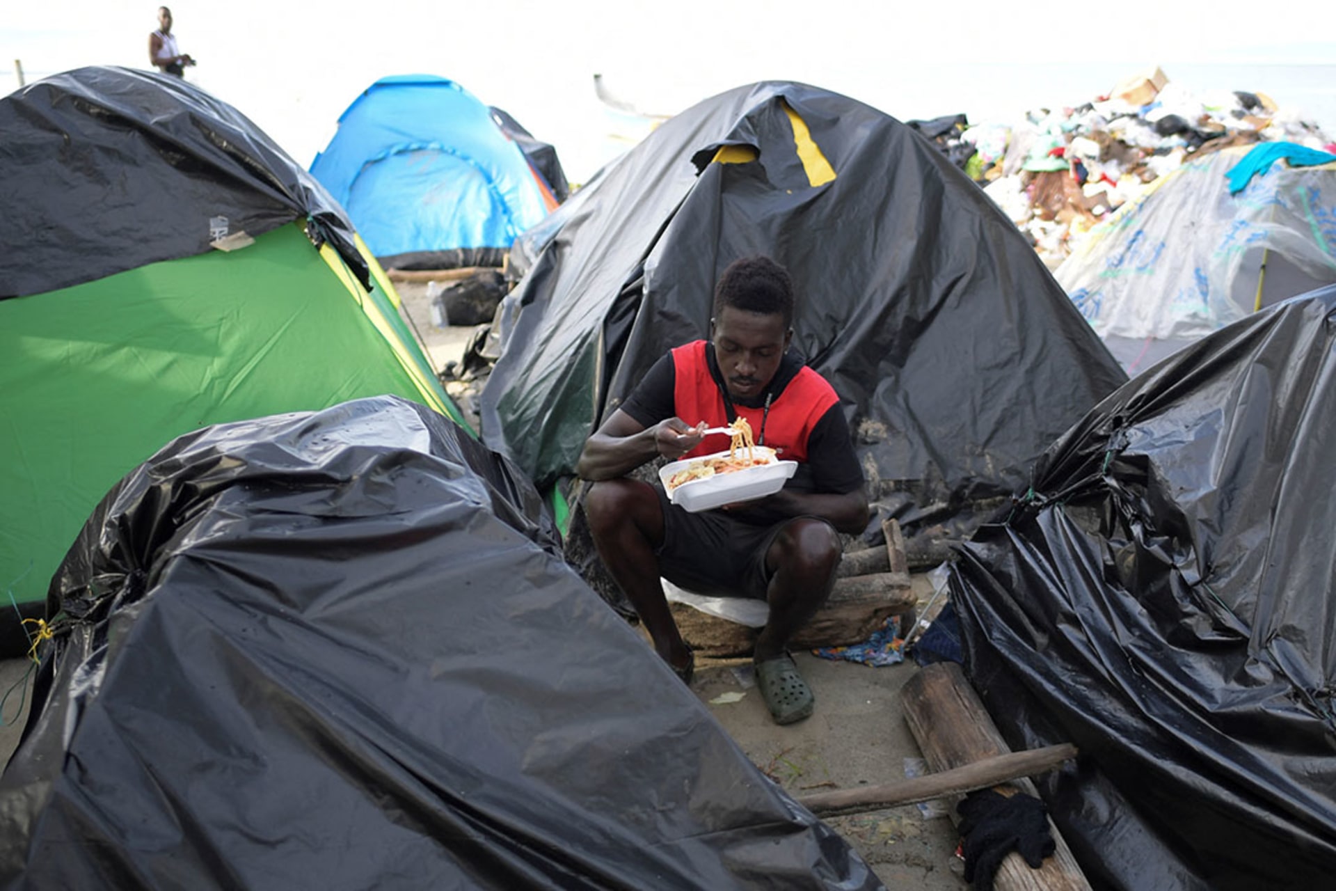 A stranded Haitian migrant eats from a take away container at a makeshift camp in Necocli, Colombia.