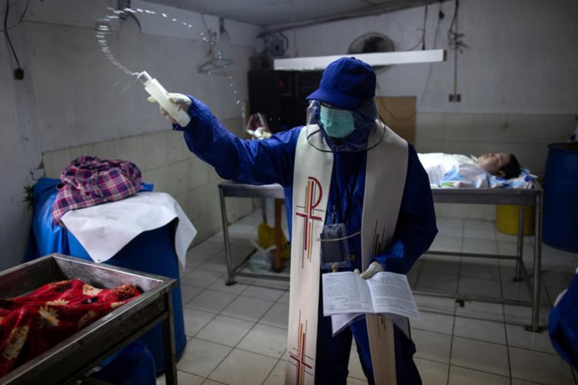 <p>PHILIPPINES (R): Priest Rey Amancio, wearing full-body gear, maintains Catholic traditions by continuing to bless the deceased in Caloocan. <span class="immersive-image__figcaption-credit">Eloisa Lopez/Reuters</span></p>
