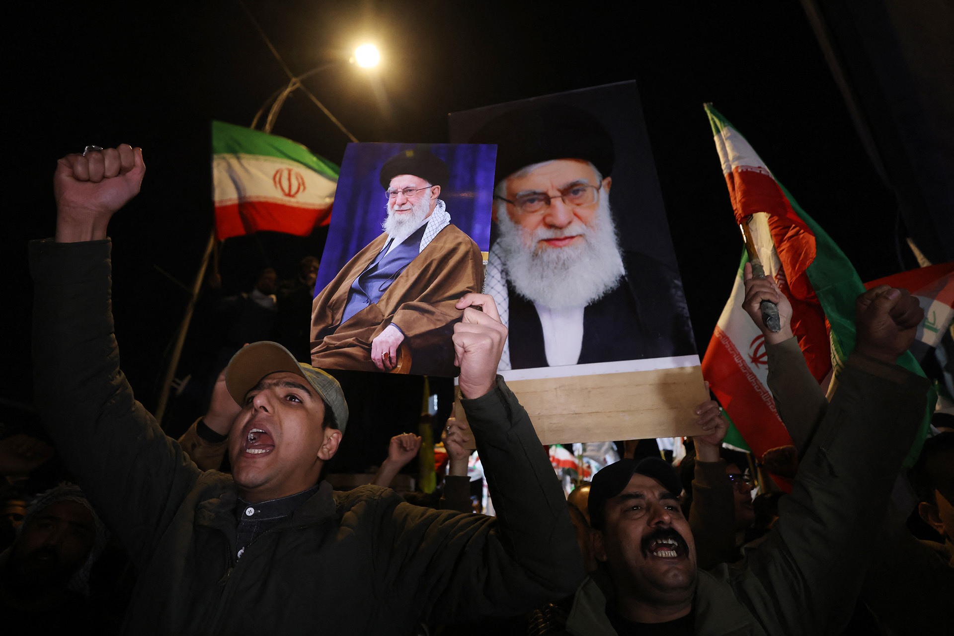 Iraqi Shiites shout slogans as they carry a portrait of Iran's Supreme Leader Ayatollah Ali Khamenei and wave Iran flags during a protest against U.S. and Israeli attacks on Iran at a bridge leading to Green Zone where the U.S. embassy is located.