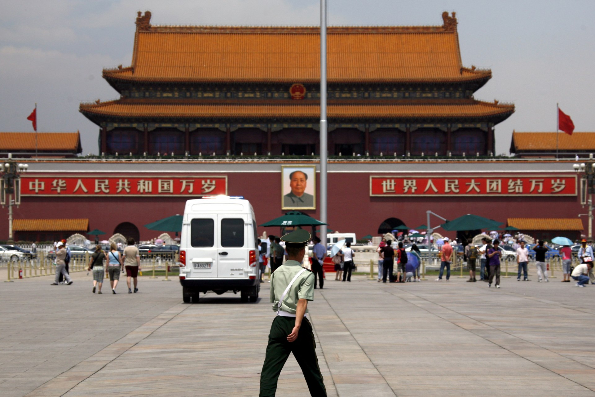 A police van sits parked in front of the giant portrait of Chairman Mao Zedong as a paramilitary policeman patrols Beijing's Tiananmen Square