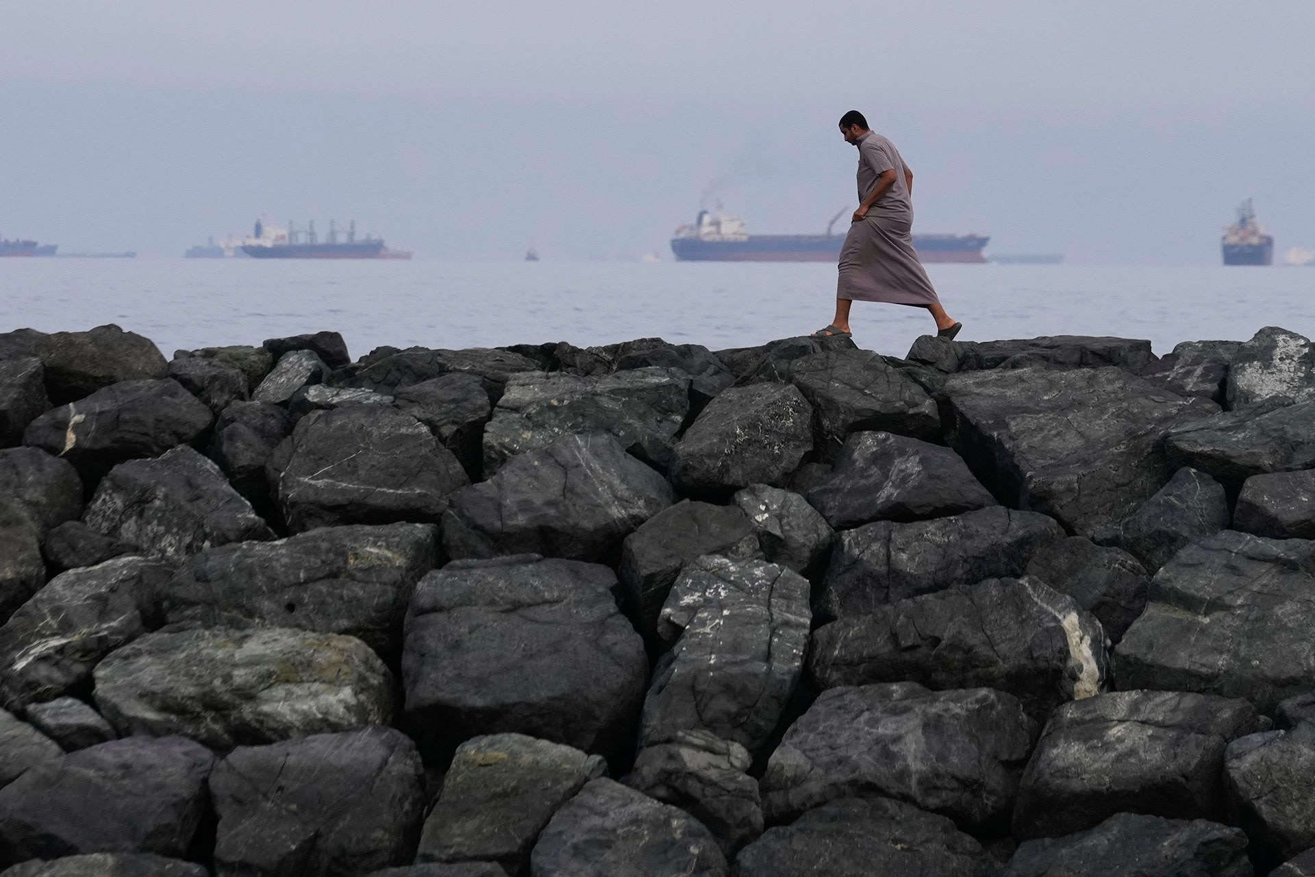 <p>A man walks along the shore as oil tankers and cargo ships line up in the Strait of Hormuz, seen from Khor Fakkan, United Arab Emirates, Wednesday, March 11, 2026.</p>
