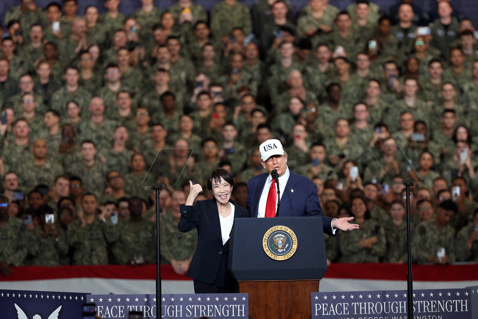 U.S. President Donald Trump speaks as Japanese Prime Minister Sanae Takaichi gestures towards military personnel, aboard the aircraft carrier USS George Washington, during their visit to the U.S. Navy's Yokosuka base in Yokosuka, Japan, on October 28, 2025.
