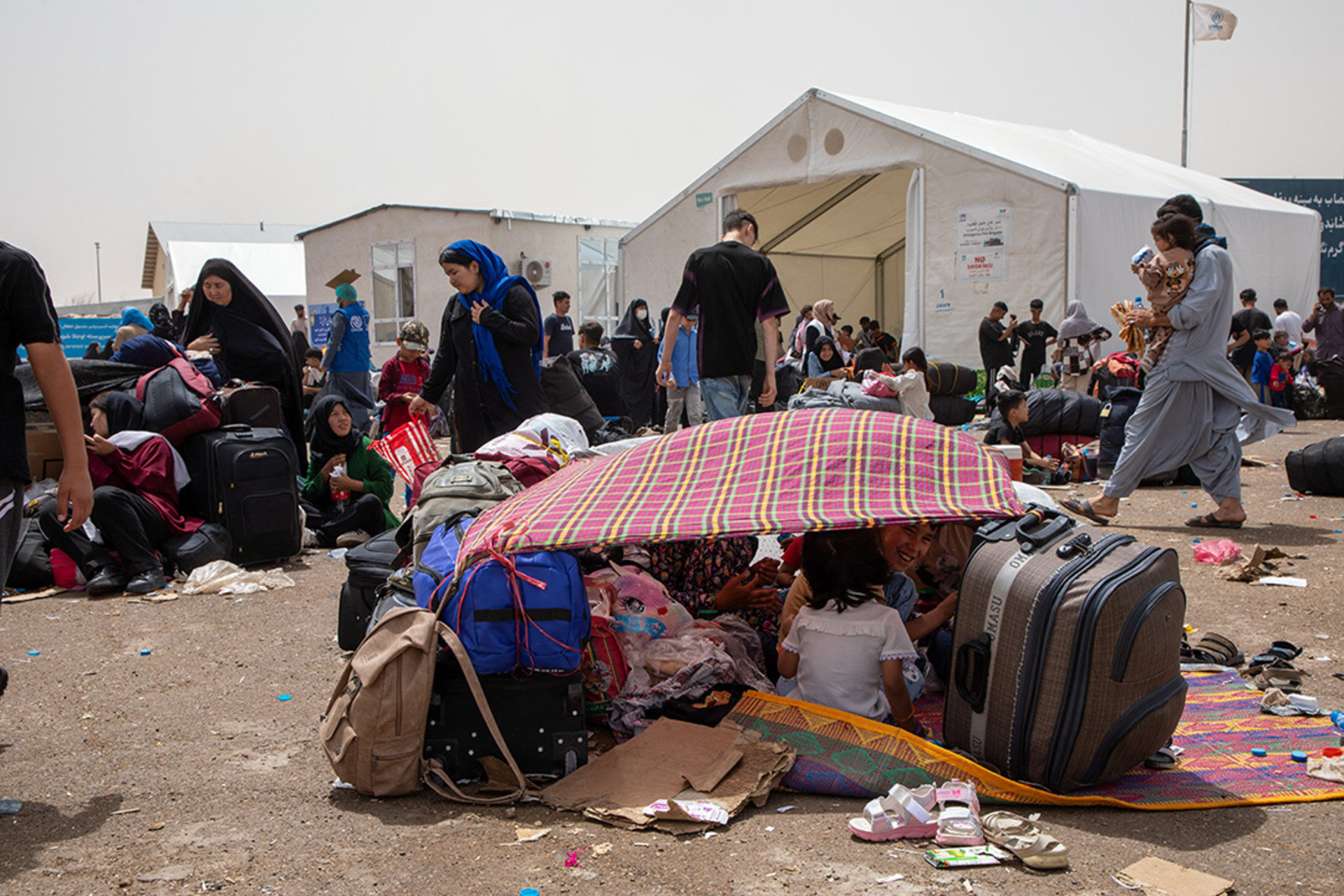 Afghan families deported from Iran rest under makeshift shelters at the Islam Qala crossing on July 4, 2025.