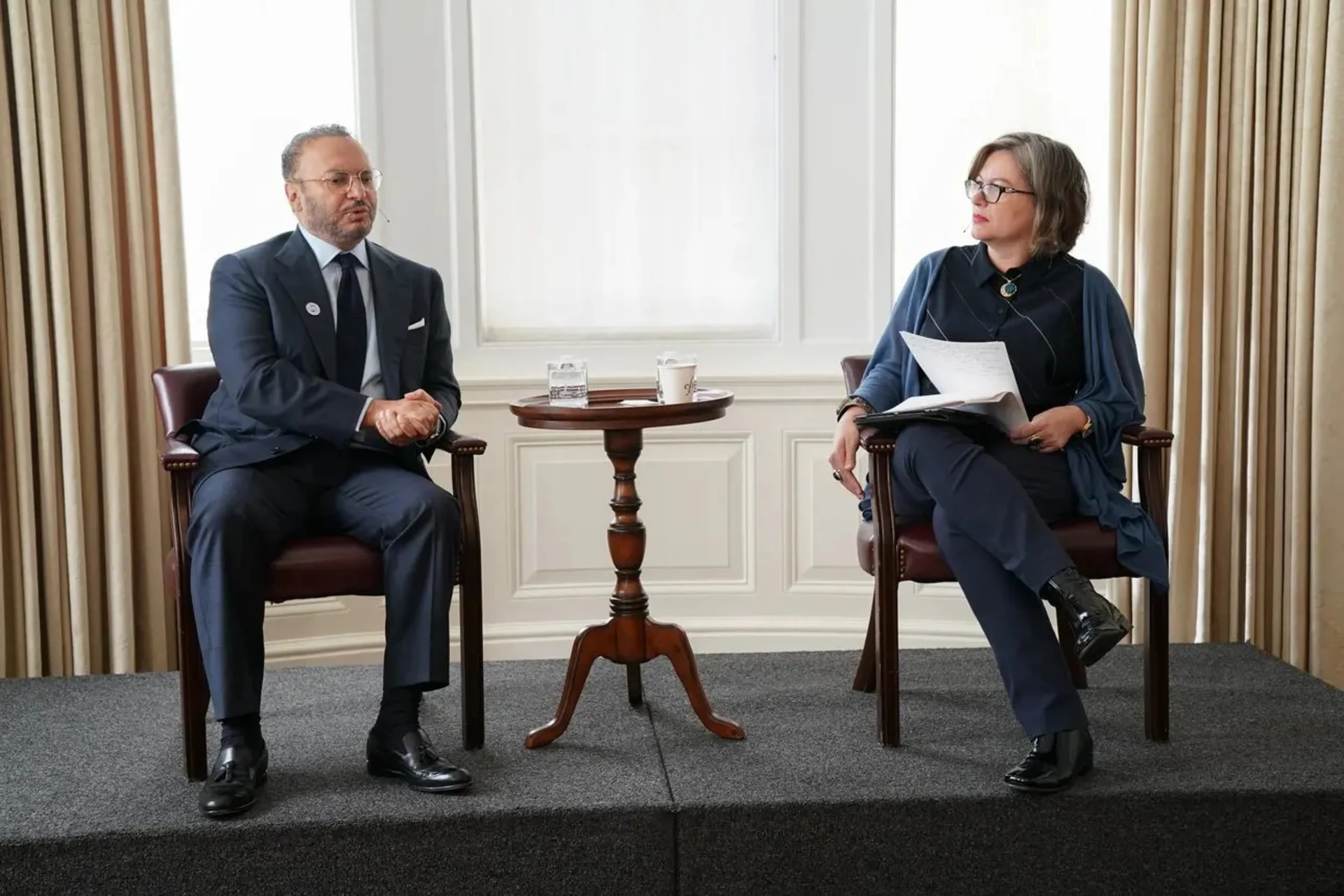 Photo of two people sitting in chairs on a stage.