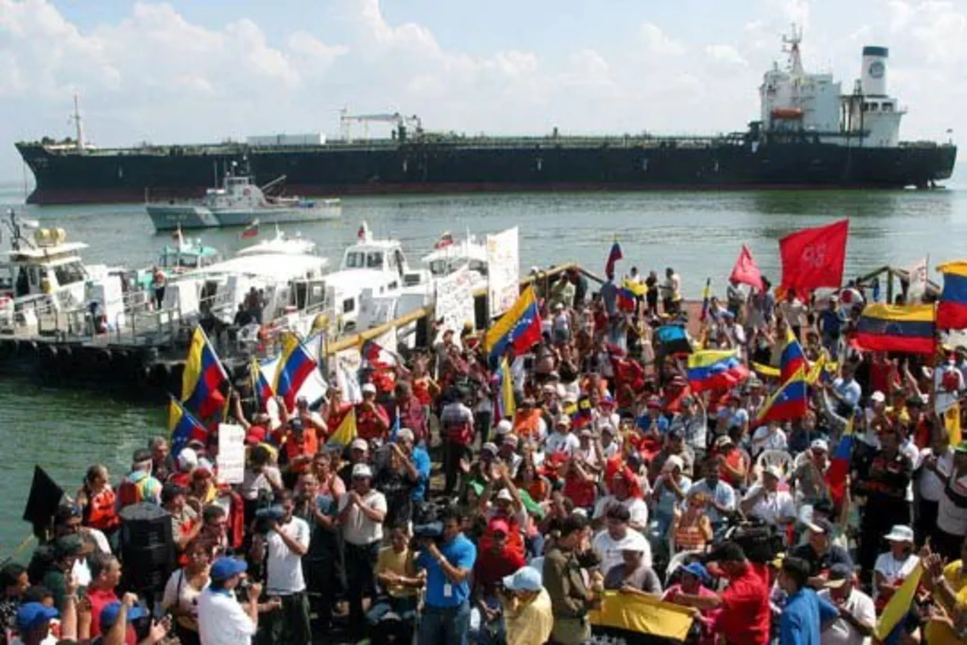Striking PDVSA oil workers in front of an anchored oil ship.