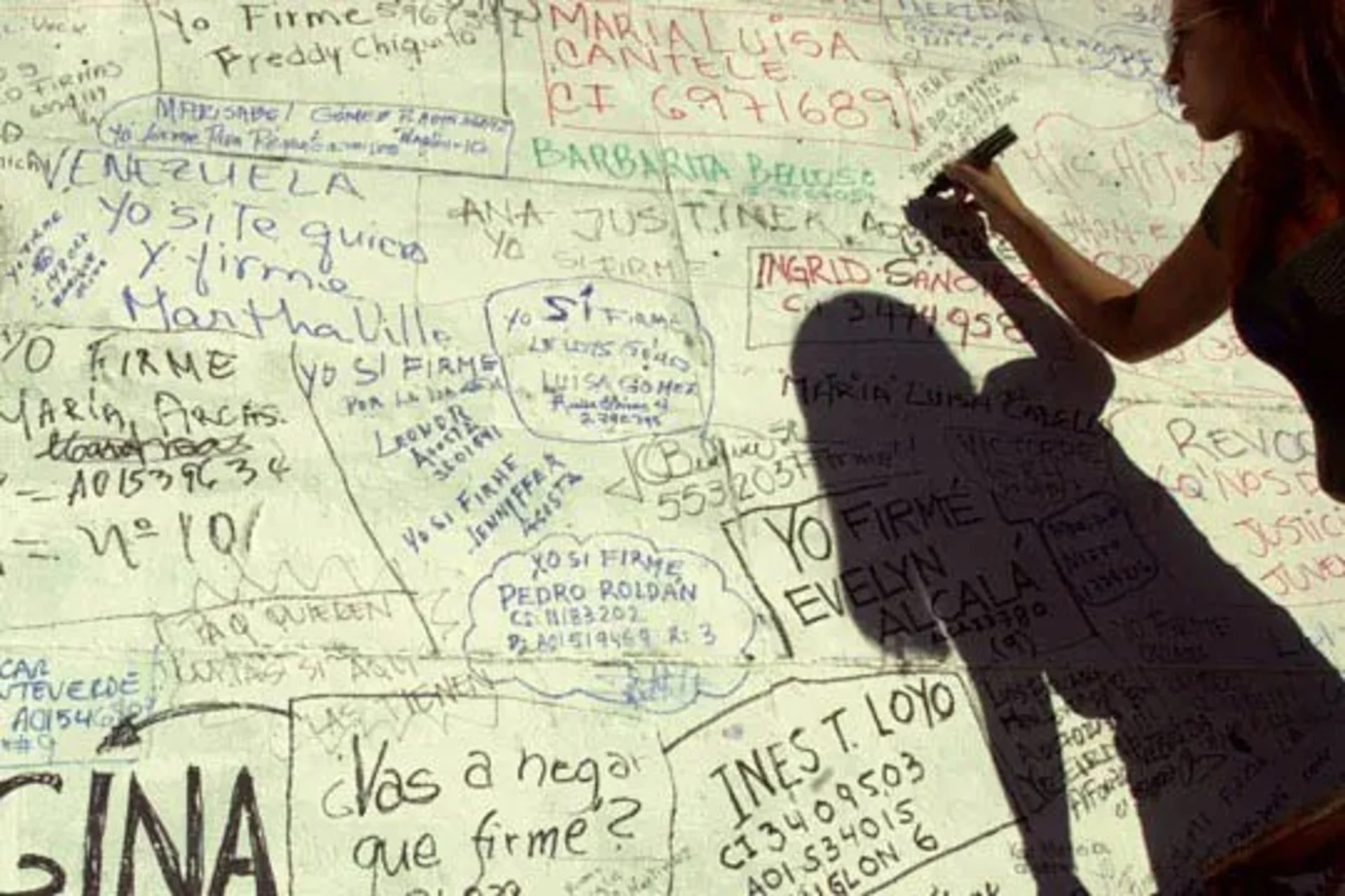 A Chavez opponent signs a petition demanding a recall referendum. 
