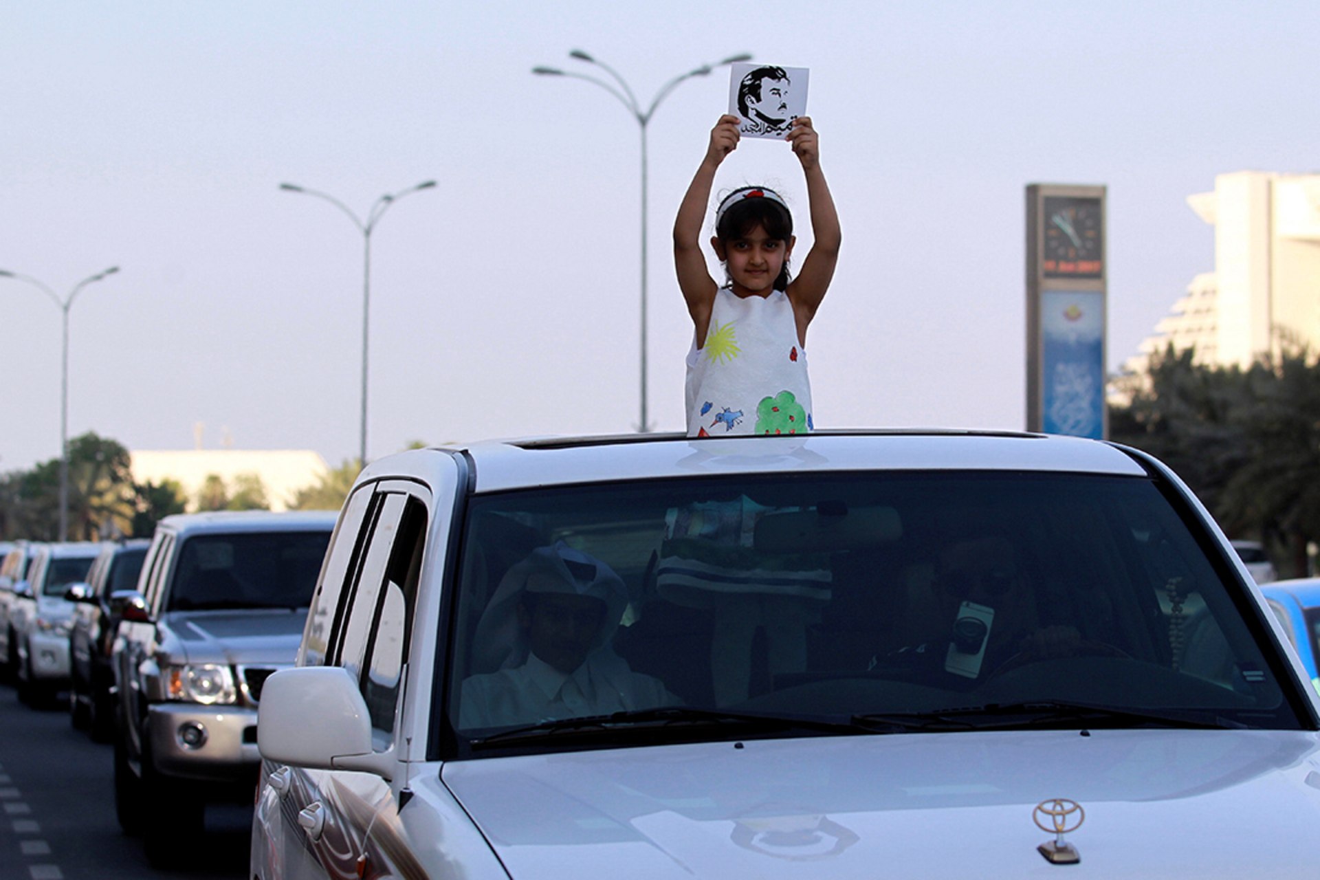 A girl holds a picture of Qatar’s emir during a demonstration in Doha.