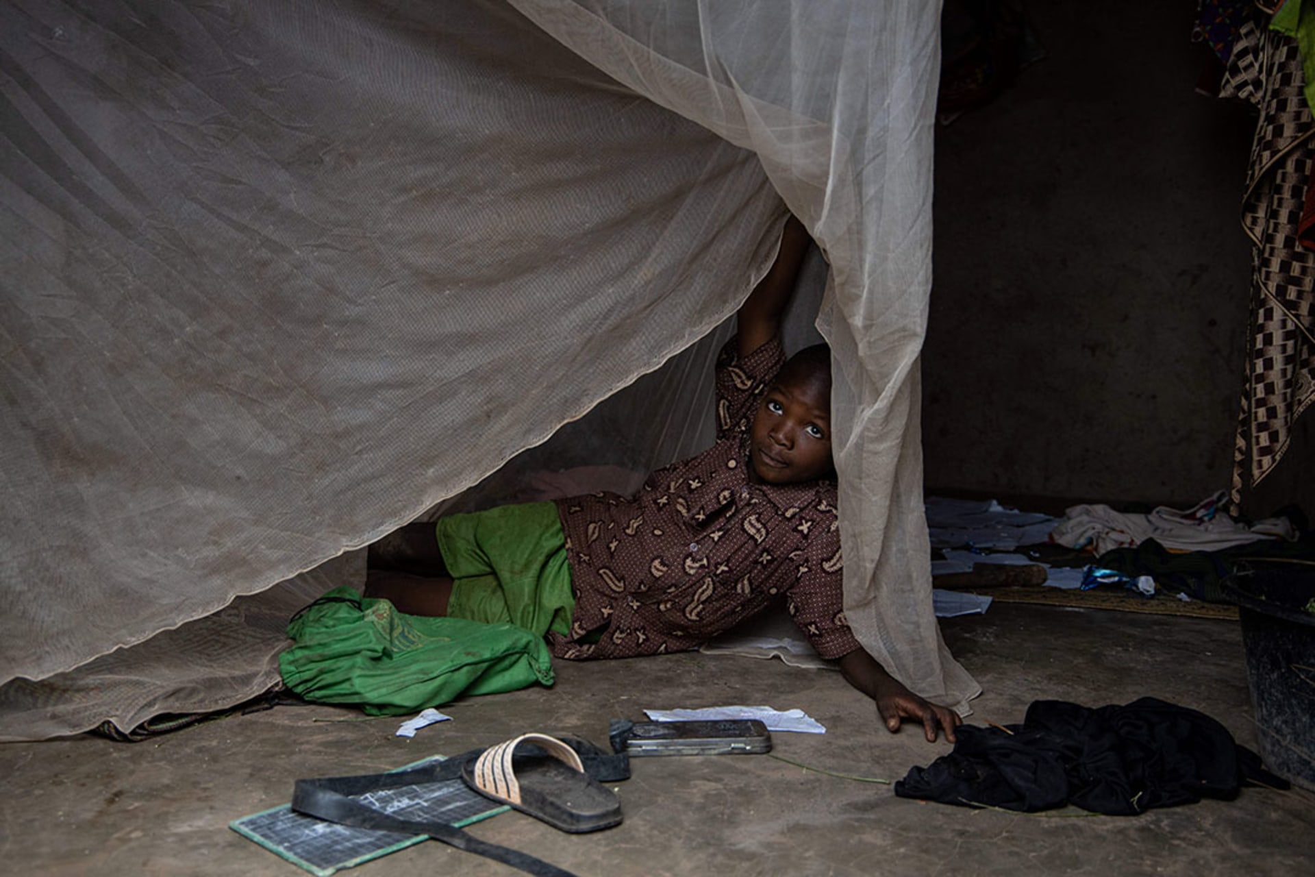 A child lifts his mosquito net in Sao, Burkina Faso, in August 2019. Olympia de Maismont/AFP/Getty Images