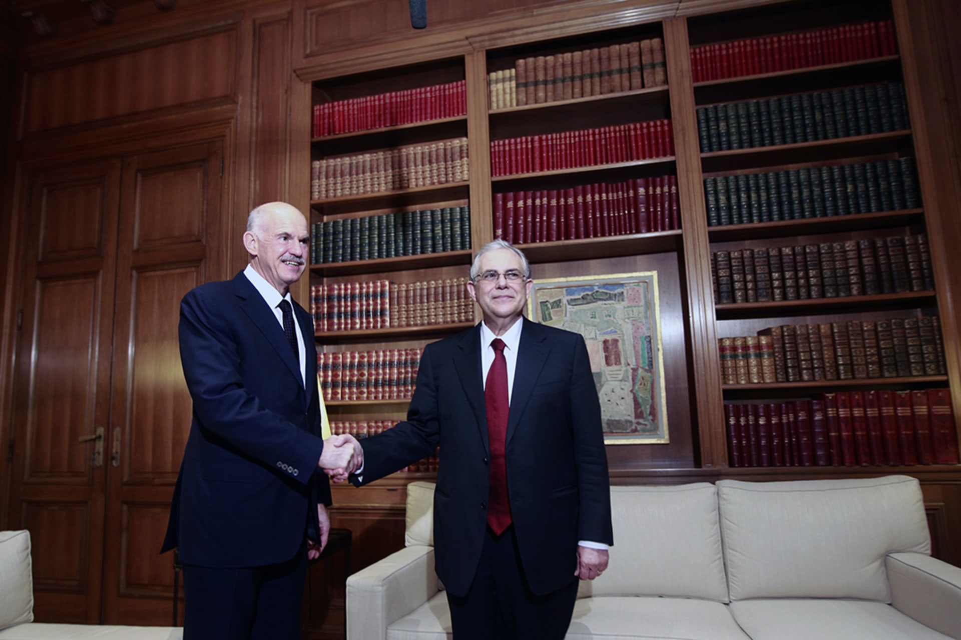 Outgoing Prime Minister George Papandreou (L) shakes hands with his successor, Lucas Papademos, at the Maximos Mansion in Athens. 
