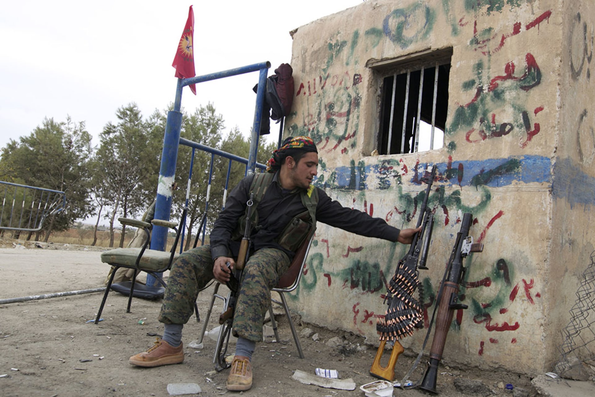 A YPG fighter sits at a checkpoint near Ras al-Ain in Syria. Kurdish militias captured the city and its surrounding villages, leading to the declaration of autonomy.