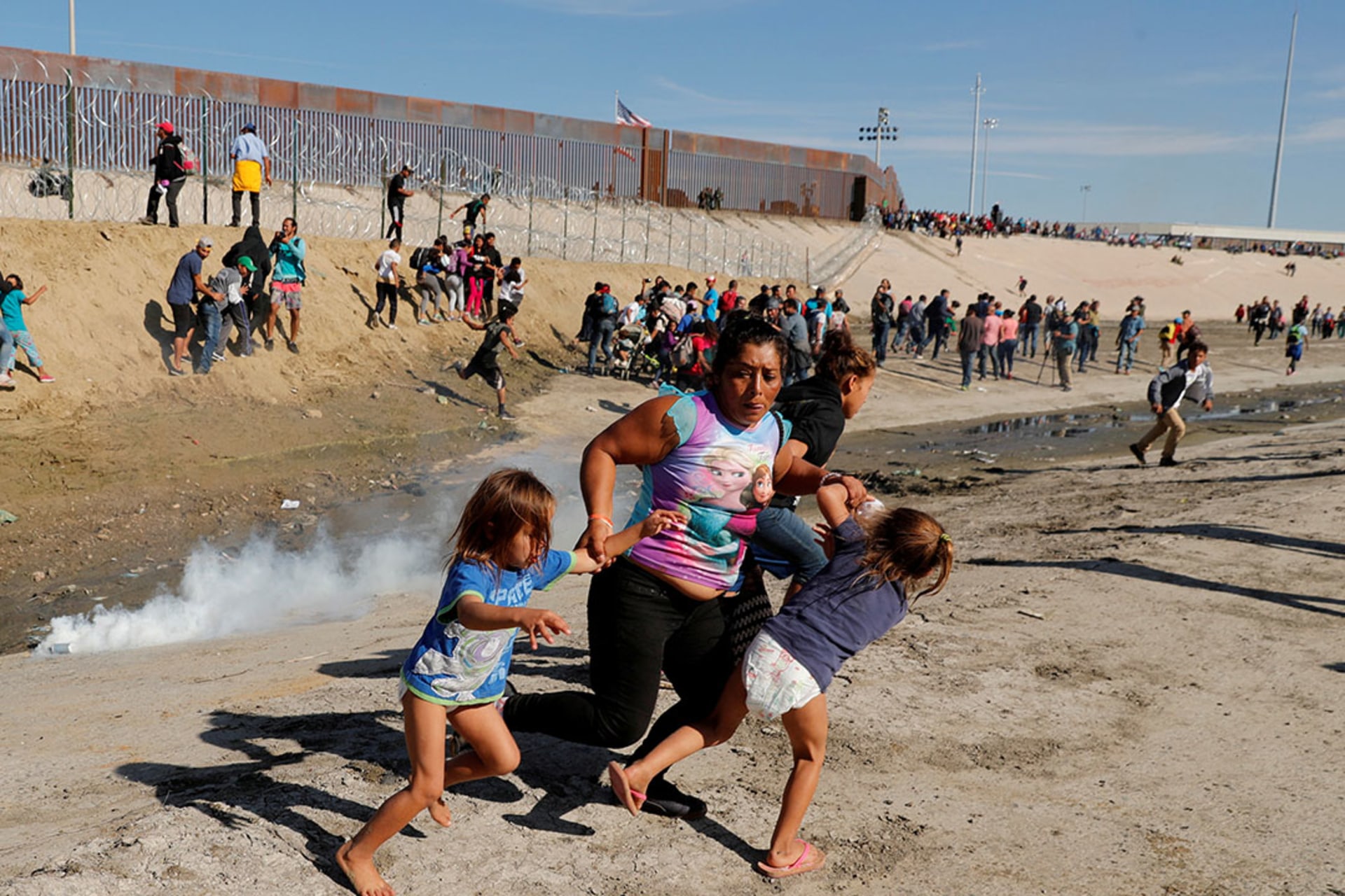 A migrant woman from Honduras, part of a caravan of thousands from Central America, runs from tear gas with her five-year-old daughters at the U.S.-Mexico border. Kim Kyung-Hoon/Reuters