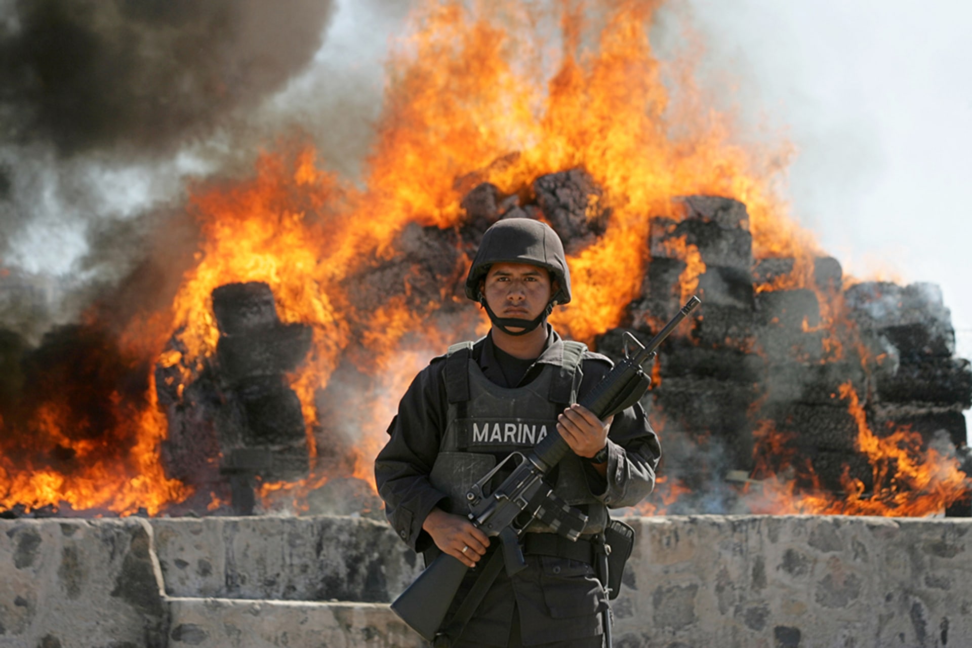 A Mexican marine stands in front of a burning pile of cocaine at a naval base in Sinaloa, Mexico, in January 2007. Daniel Aguilar/Reuters