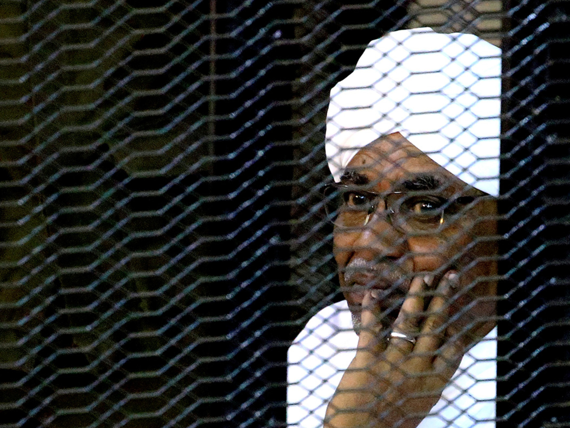 Former Sudanese President Omar al-Bashir sits inside a cage at a Khartoum courthouse. 
