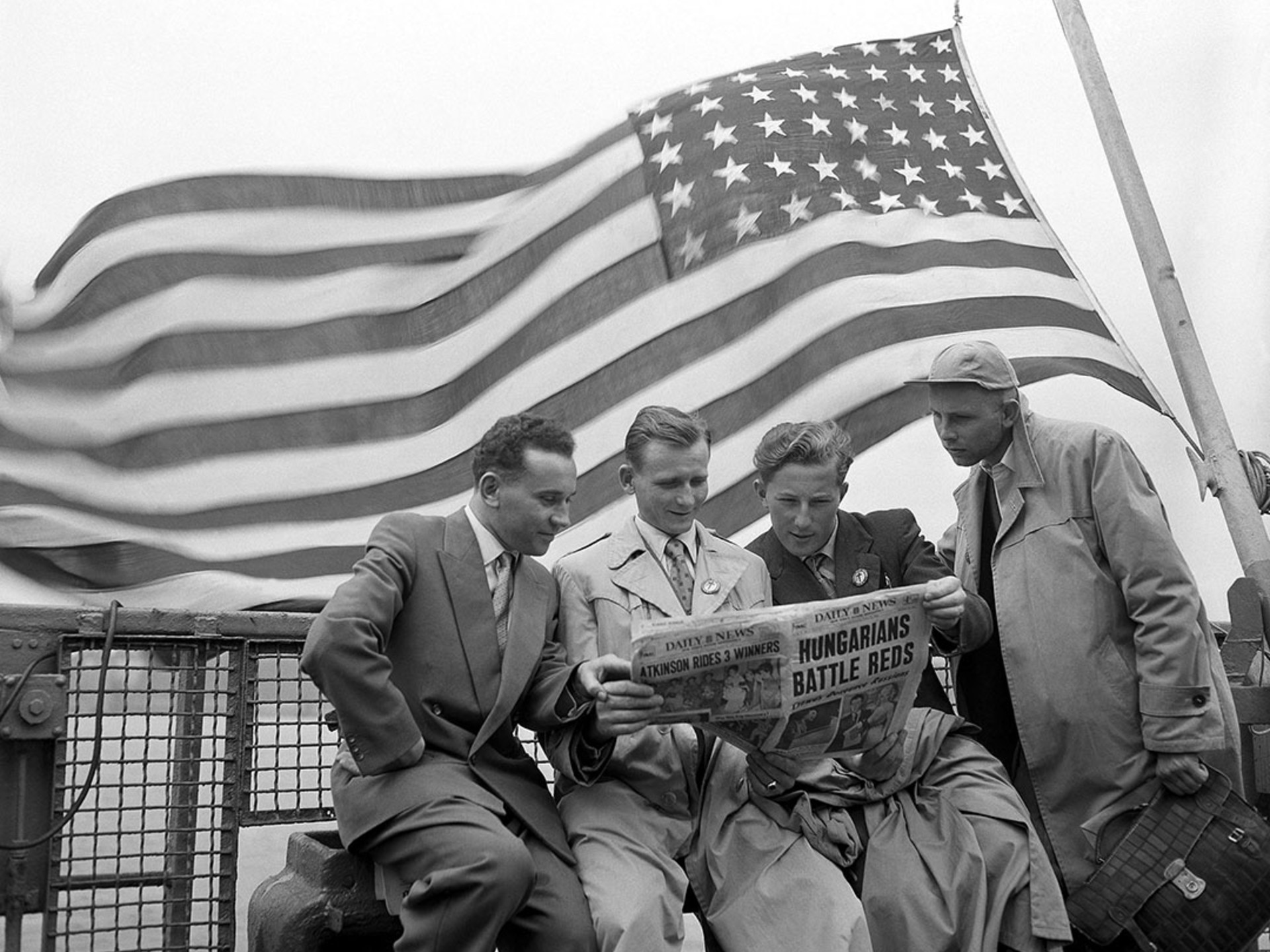 Refugees read about unrest in Hungary as they arrive by boat in New York City. AP Images