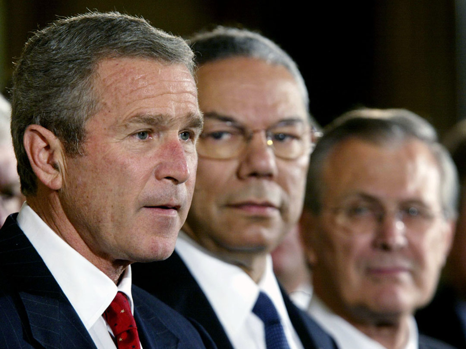 President Bush, joined by Secretary of State Colin Powell and Secretary of Defense Donald Rumsfeld, speaks at the signing of the congressional resolution authorizing war in Iraq. Kevin Lamarque/Reuters